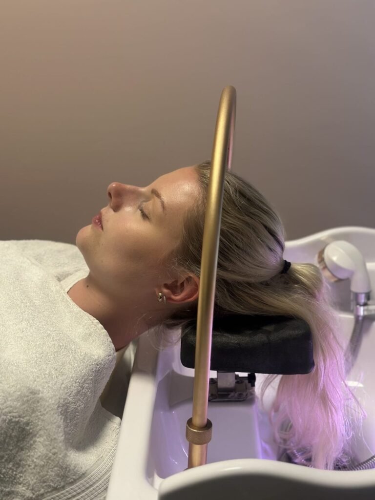 Warm water ritual: client under the head spa arc at partner salon Belliza