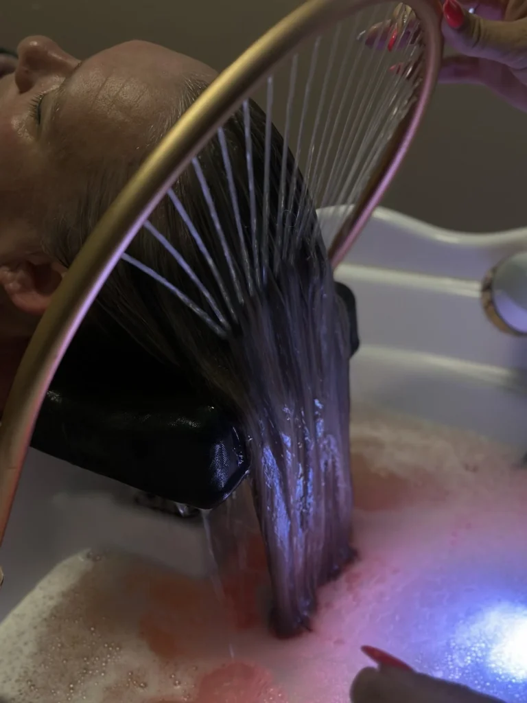 Close-up of the head spa water arch rinsing hair over the basin, partner salon Belliza